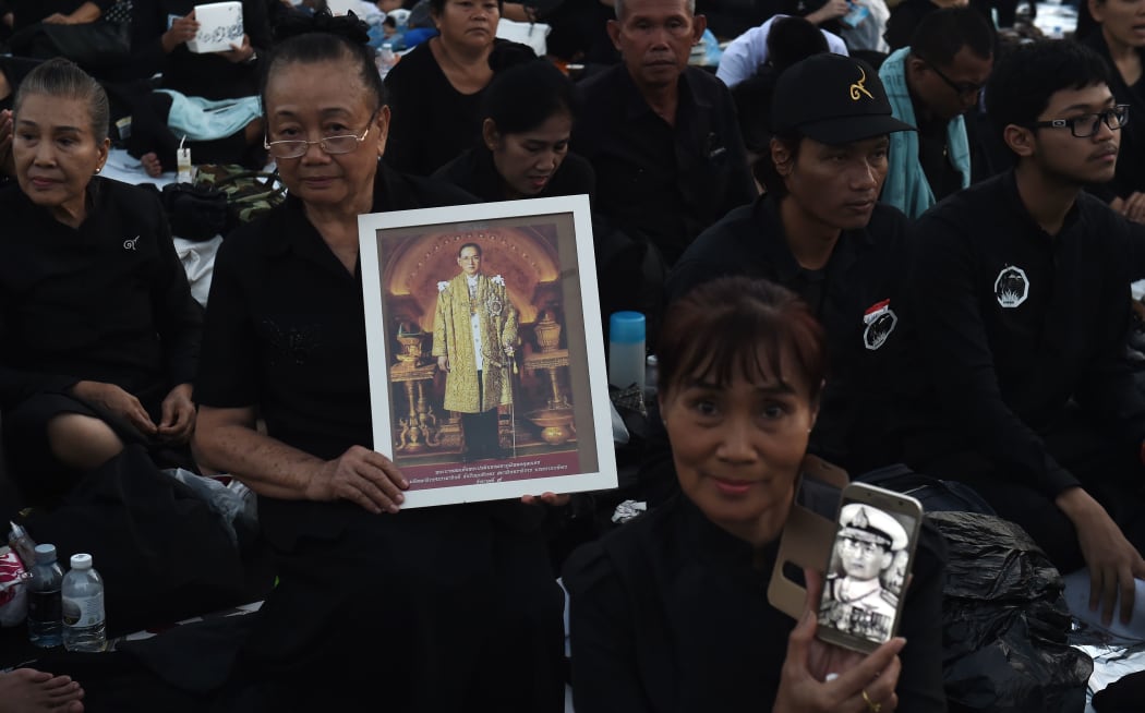 Mourners hold images of the late Thai King.