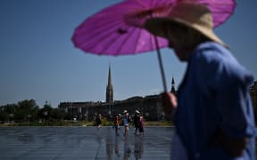 Visitors walk across the Mirroir d'Eau reflecting pool to cool down in Bordeaux, southwestern France on June 23, 2026, as France experiences a heatwave. (Photo by Christophe ARCHAMBAULT / AFP)