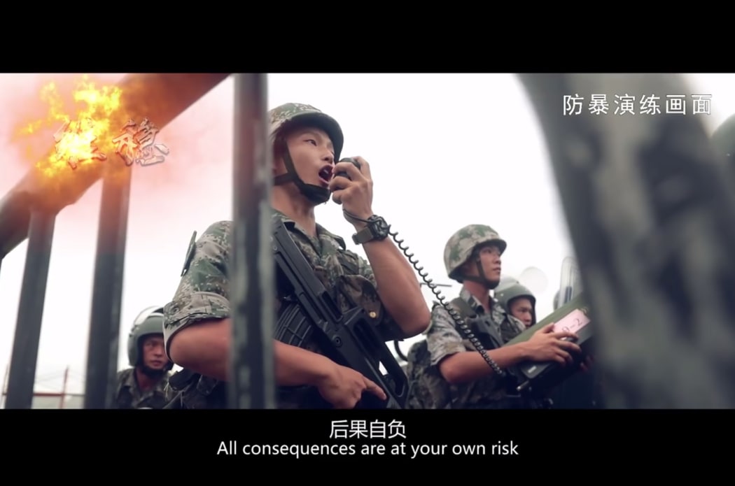This screengrab taken from undated handout three-minute promotional video received on August 1, 2019 from China's People's Liberation Army (PLA) Hong Kong Garrison shows PLA soldiers warning "protesters" during an "anti-riot" drill in Hong Kong.
