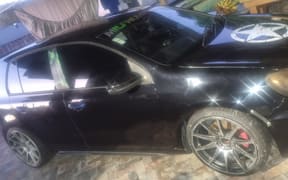 The car - with a license plate RBZ53 - is a dark coloured hatchback.