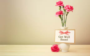 43085943 - get well soon message with pink carnations in a white vase