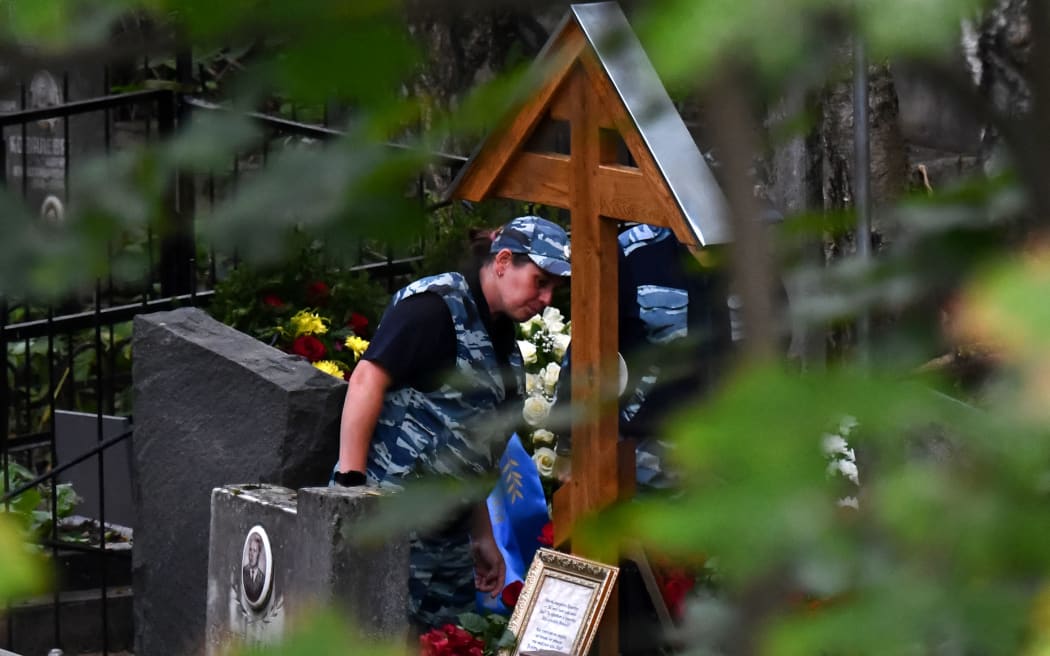 Police officers stand by the grave of Wagner private mercenary group chief Yevgeny Prigozhin, who was killed in a private jet crash in the Tver region last week, after his funeral at the Porokhovskoye cemetery in Saint Petersburg on August 29, 2023. (Photo by Olga MALTSEVA / AFP)