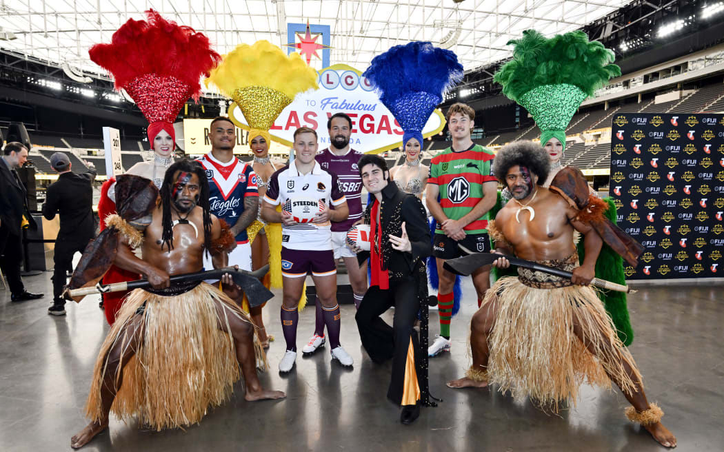 National Rugby League players Spencer Leniu (3rd L), Billy Walters (5th L), Aaron Woods (C) and Campbell Graham (3rd R) pose with Las Vegas showgirls, an Elvis impersonator and Fijian warriors.