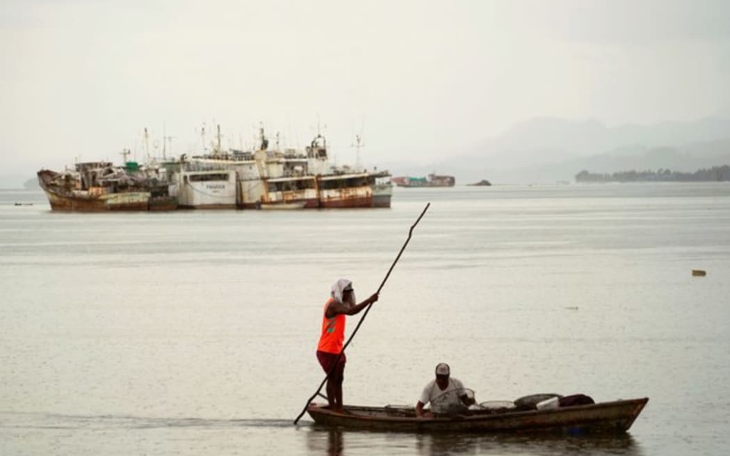 Fijian fishermen in Suva harbor with some of the abandoned fishing boats in the background. Pictured on Feb. 15, 2025.