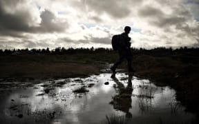 A Ukrainian soldier walks through water during a training exercises with French soldiers at a French military camp in France in November 2023. On their stomachs, the Ukrainian soldiers advance slowly at the edge of the forest in support of an assault group that is seizing the enemy trench: in a military camp in France, they are being trained in combat before leaving for the front. (Photo by OLIVIER CHASSIGNOLE / AFP) / EMBARGO UNTIL MONDAY NOVEMBER 13, 2023,  00.01
