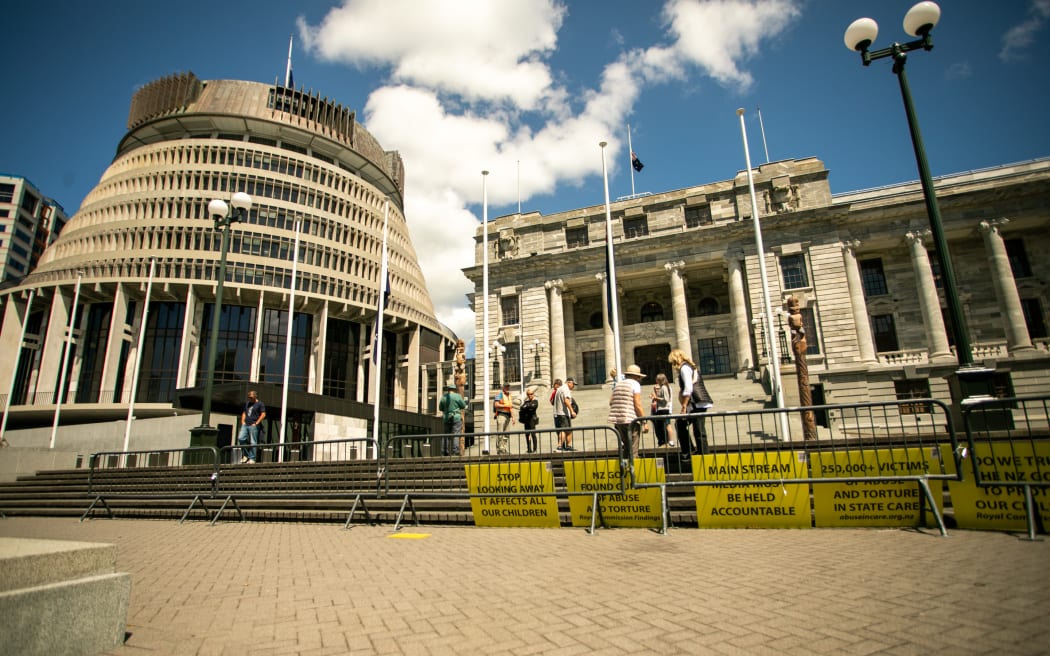 Signs from protestors sit outside Parliament during the apology for abuse in state care