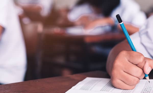 Exam with uniform school student doing educational test with stress in classroom.16:9 style