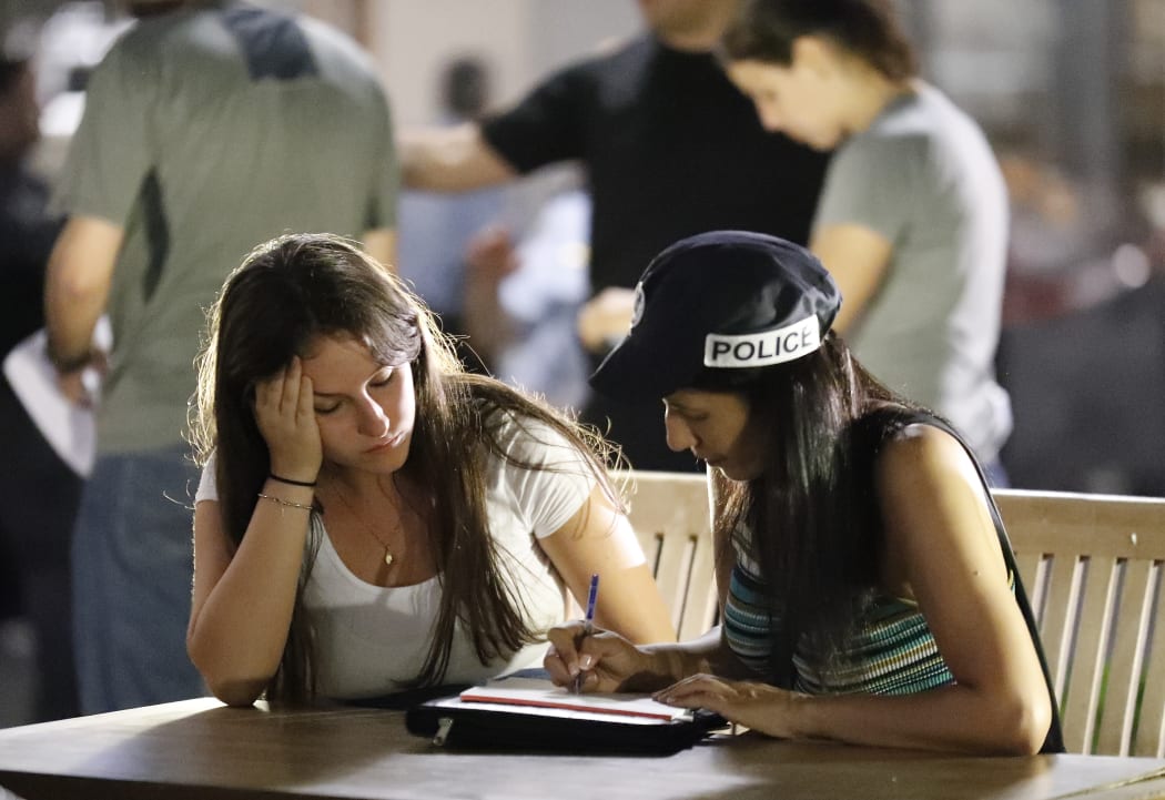 An Israeli policewoman (right) interviews a witness at the site of a shooting attack in Tel Aviv.