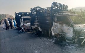 Security personnel stand near charred vehicles at the site of a shooting on a highway in Musakhail district, Balochistan province on 26 August 2024.