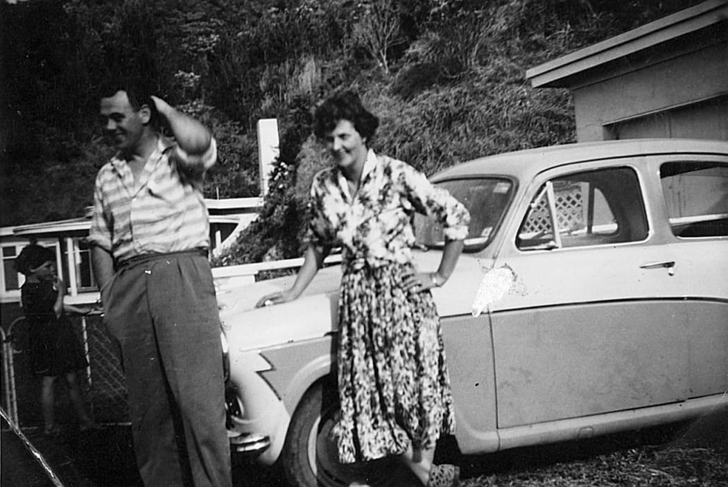 A black and white photo of Bill and Colleen Hopkins, Bruce's parents, leaning on their car.