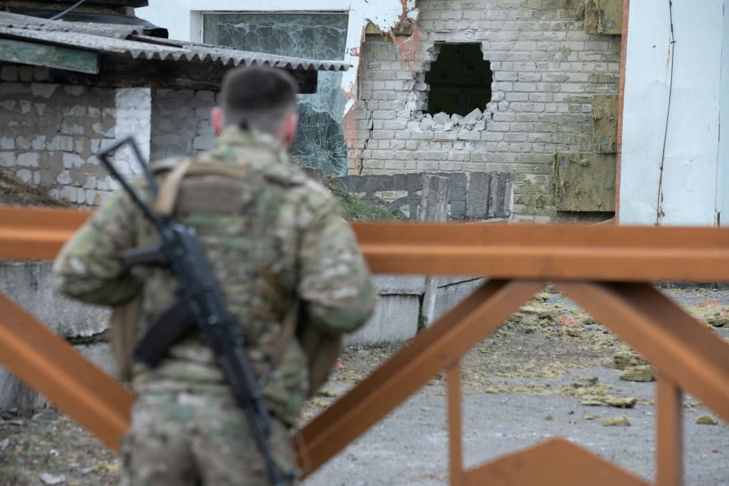 A Ukrainian soldier looks at debris after the reported shelling of a kindergarten in the settlement of Stanytsia Luhanska, on February 17, 2022.