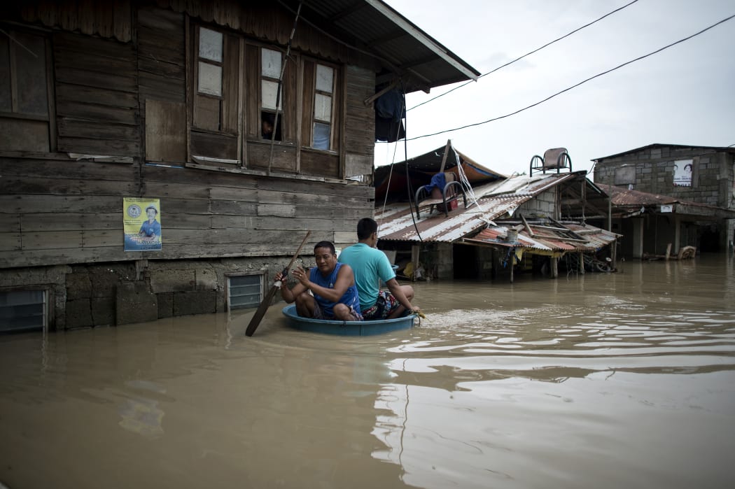 Men use a basin to cross a flooded street in the aftermath of Super Typhoon Mangkhut at Salonga Compound in Calumpit, Bulacan on September 16, 2018.