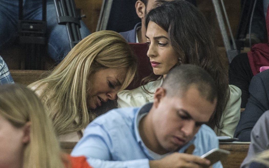 Marwa Fahmy (C), the wife of Canadian Al-Jazeera journalist Mohamed Fahmy (unseen), reacts as she sits next to Amal Clooney (R), the human rights lawyer representing Fahmy, during the trial of her husband and Egyptian Baher Mohamed,
