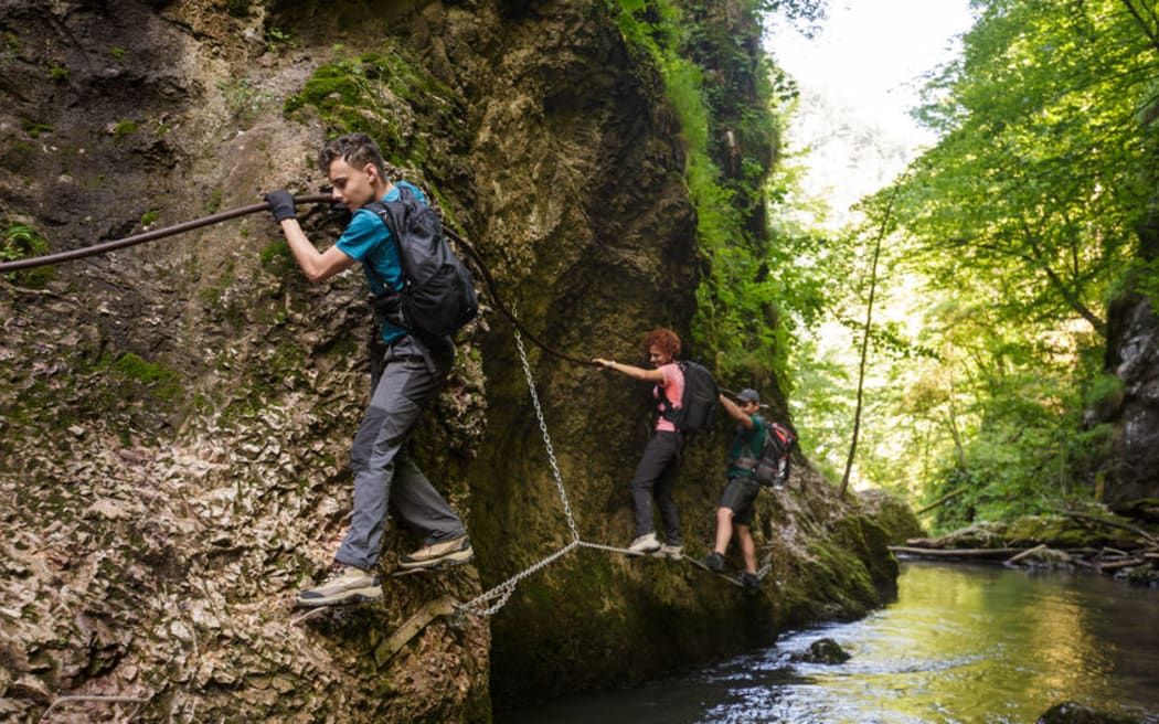 A photo of father hiking with his children above a river