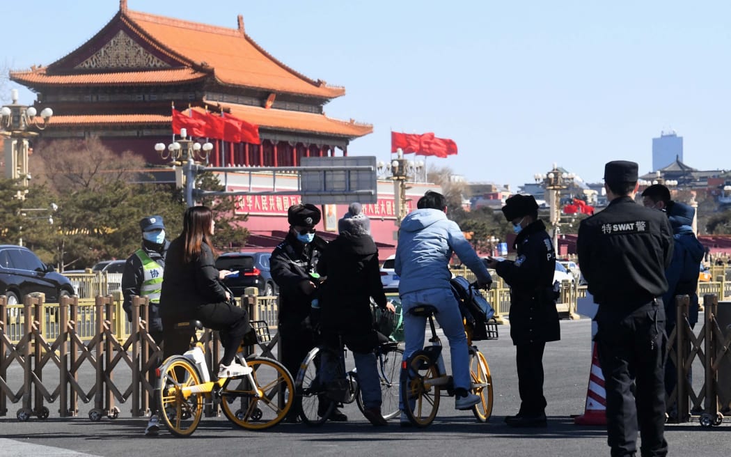 Policemen check the identification cards of bikers passing the Tiananmen area near the Great Hall of the People ahead of the opening ceremony of the National People's Congress (NPC) in Beijing on March 5, 2022.