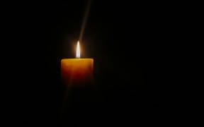 A photo of a single candle in the dark.