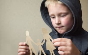A photo of a boy with a paper cut out family holding hands