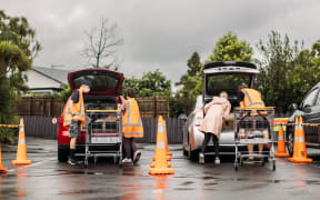 Volunteers at the Visionwest Waka Whakakitenga Drive-Through Christmas Foodbank load up car boots with parcels