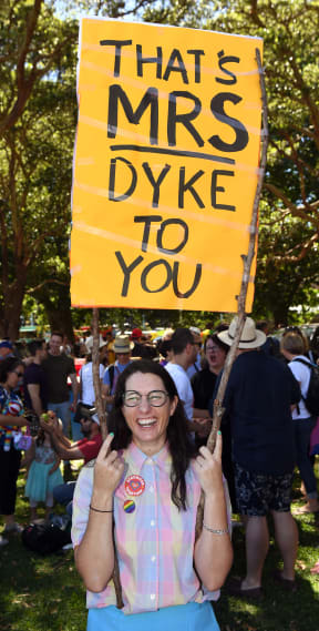 A woman holds a banner as supporters of the same-sex marriage "Yes" vote gather to celebrate the announcement in a Sydney park.