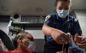 A Louisville medic helps a woman experiencing a Covid-19 emergency. Louisville Metro EMS is experiencing a surge in patients needing emergency treatment and transport.