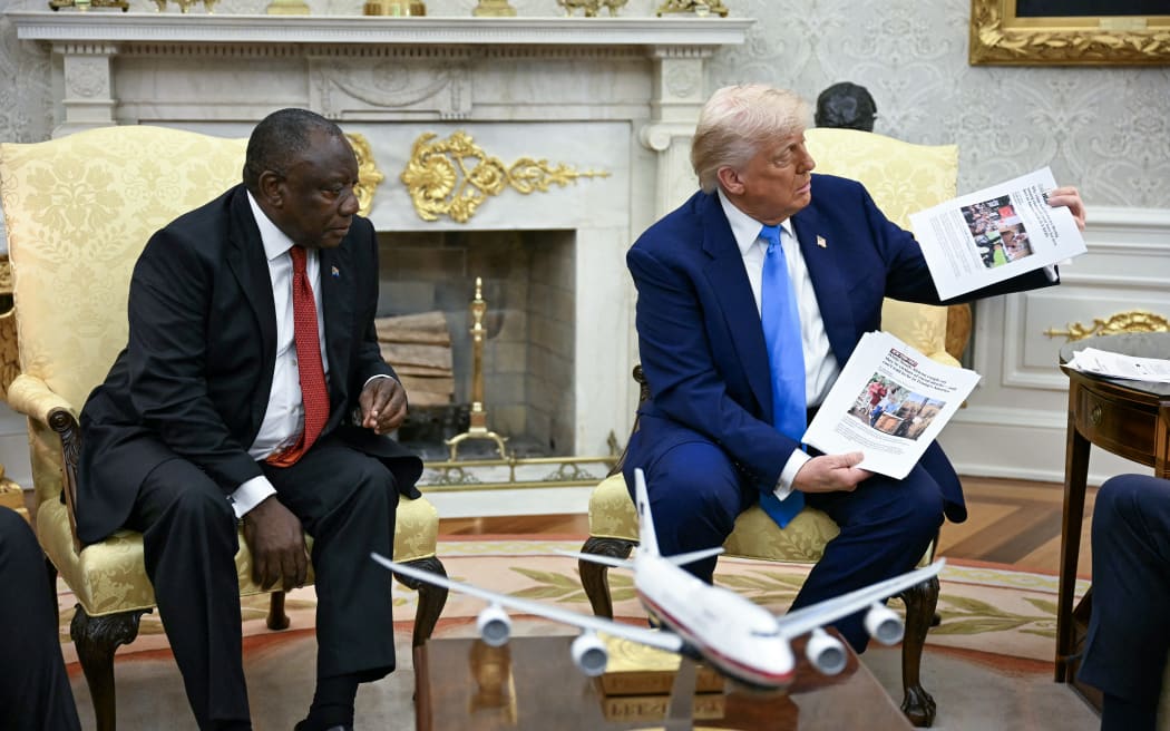 US President Donald Trump shows pictures as he meets with South African President Cyril Ramaphosa in the Oval Office of the White House in Washington, DC, on May 21, 2025. South African President Cyril Ramaphosa meets Donald Trump on Wednesday amid tensions over Washington's resettlement of white Afrikaners that the US president claims are the victims of "genocide."