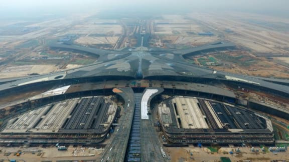 staff members working on an overpass in front of the terminal of a new airport under construction in Beijing, capital of China.