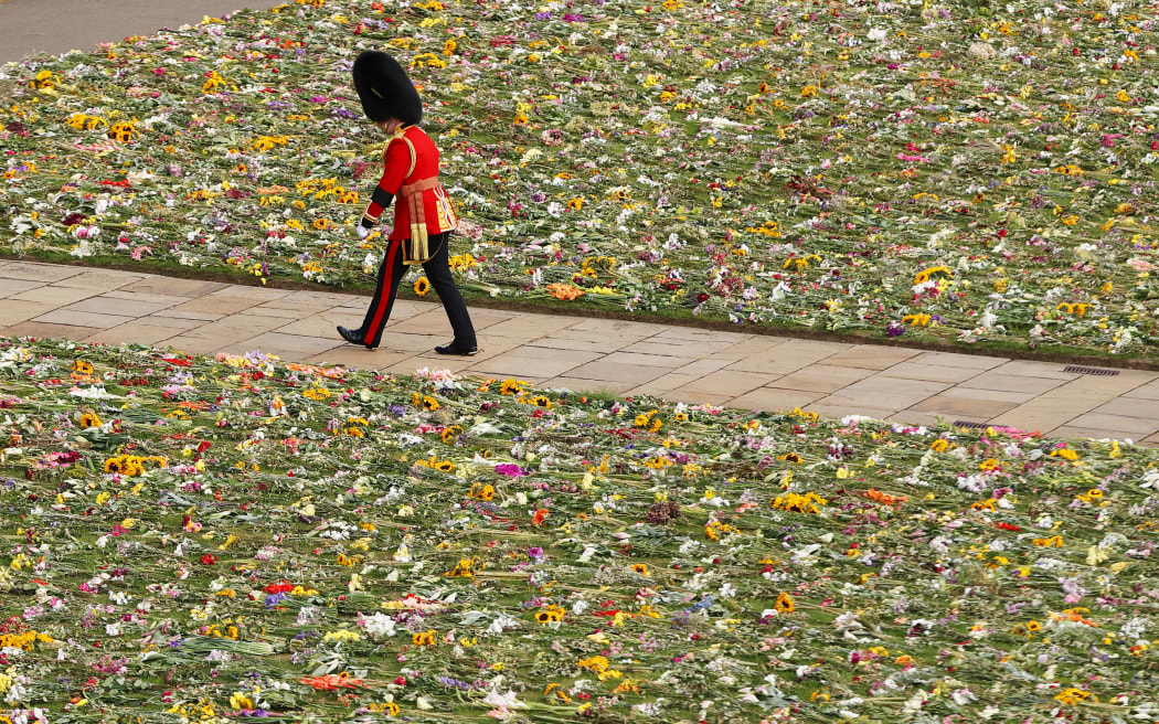 A member of the Coldstream Guards is seen walking past a bed of flowers during the State Funeral of Queen Elizabeth II on September 19, 2022 in London, England.
