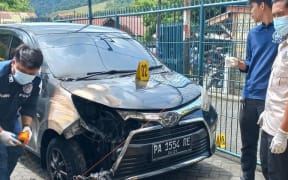 Area residents help put out a fire around the Jubi editorial office that damaged two vehicles in Jayapura, in Indonesia’s Papua region, Oct. 16, 2024.