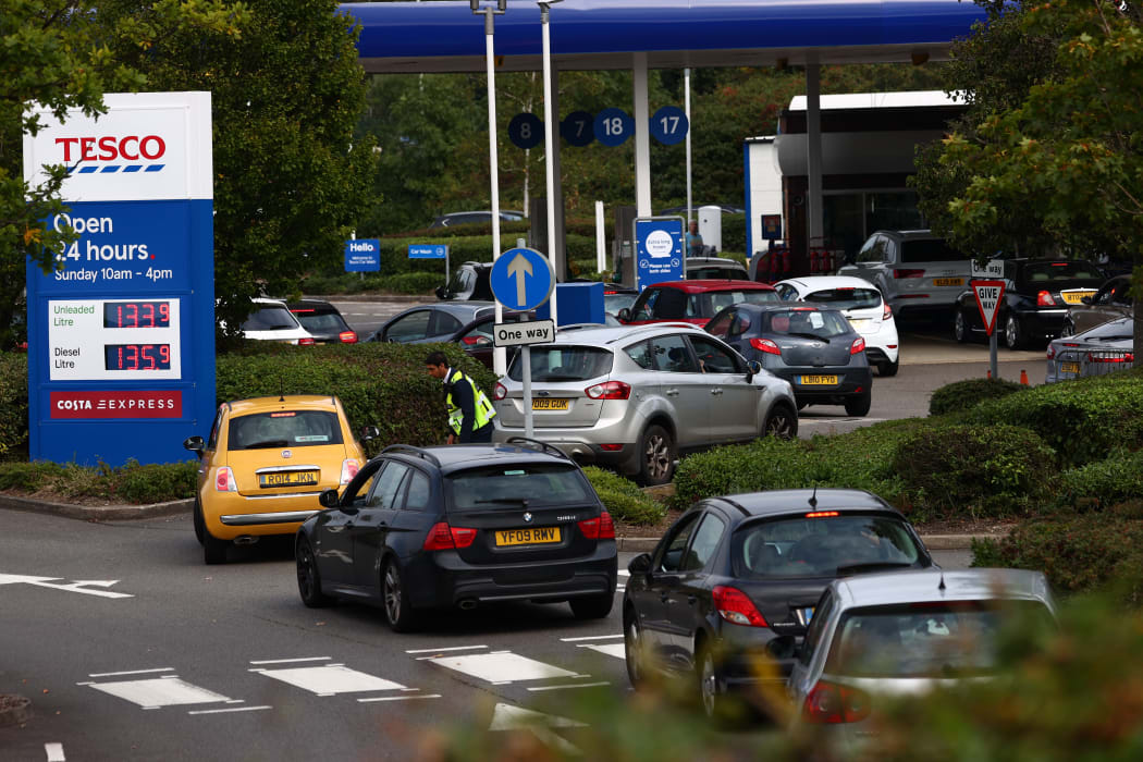A security guard assists drivers queuing to fill up at a Tesco petrol station in Camberley, west of London, on 26 September 2021.