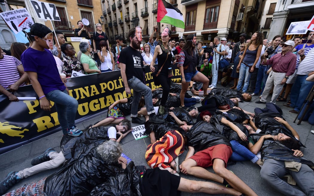 People lie on the ground in plastic bags during a rally in support of migrants and refugees as part of the European Day of Action in Madrid on September 12, 2015.