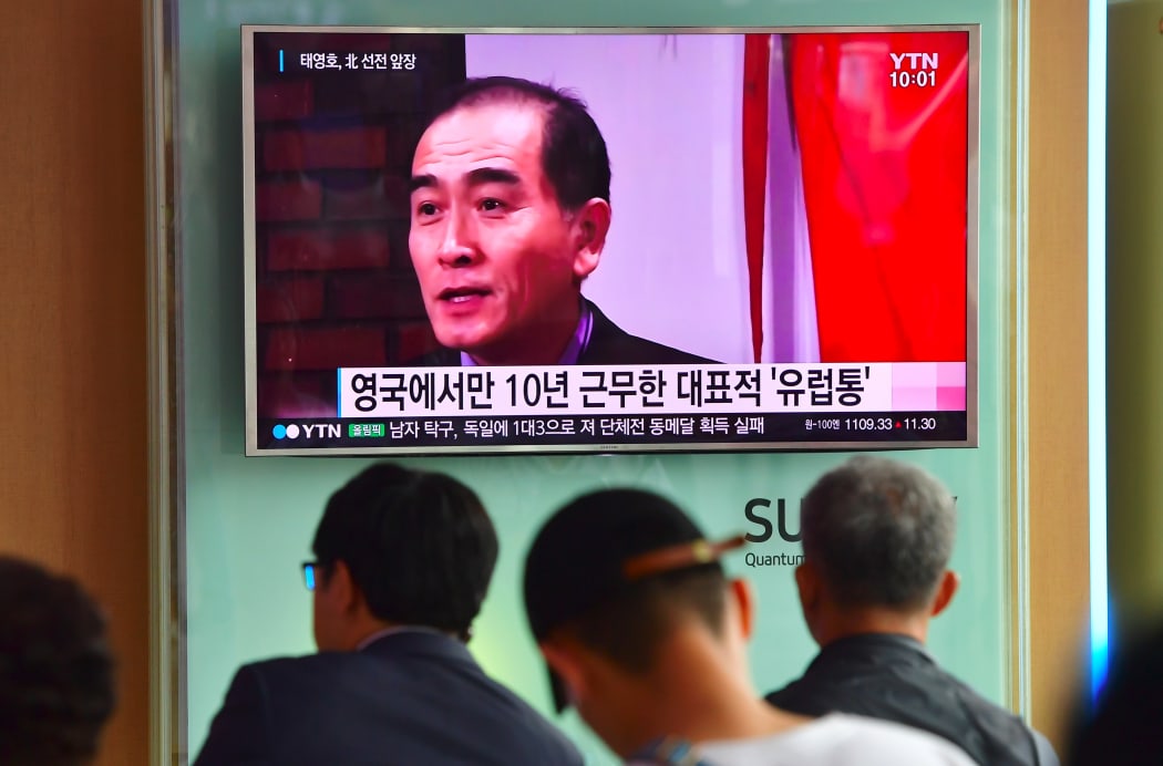 People watching a news broadcast showing file footage of Thae Yong-ho at a railway station in Seoul.