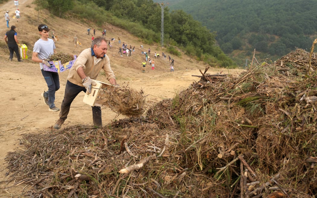 People carry out mountain clearing work in anticipation of the possible arrival of the fire from the Picos de Europa National Park blaze, in the town of Riano, Leon province, Spain on August 18, 2025. Thousands of firefighters backed by the military and water-bombing aircraft today battled dozens of wildfires across Spain and Portugal, as the death toll increased to six since the outbreaks began. In Spain wildfires have burnt the equivalent of nearly half a million football fields this year, setting a new record, according to data from the European Forest Fire Information System (Effis) today. The 2025 fires have so far burnt more than 343,000 hectares (848,000 acres), surpassing the previous record for the period of 306,000 hectares, set in 2022. (Photo by CESAR MANSO / AFP)