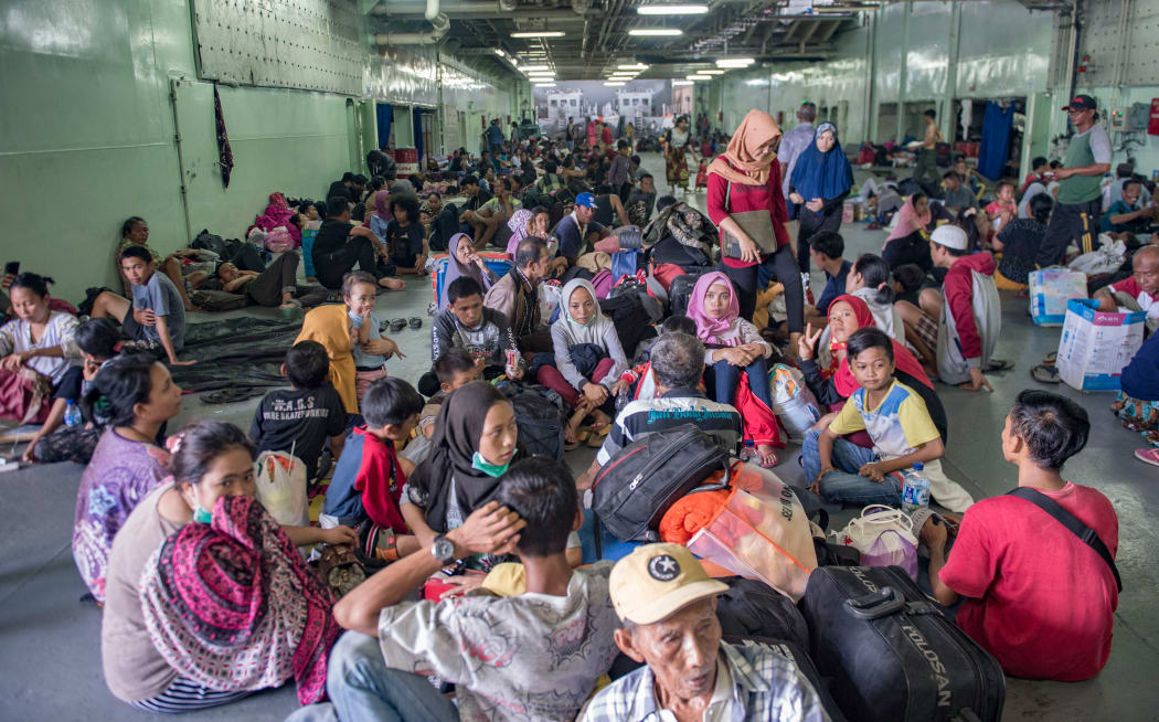 Quake-affected people sit together on board the Indonesian Navy warship KRI Makassar (590) as they prepare to be evacuated from Palu.