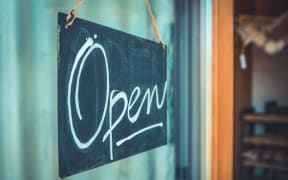 Open sign hanging in the door of a shop.