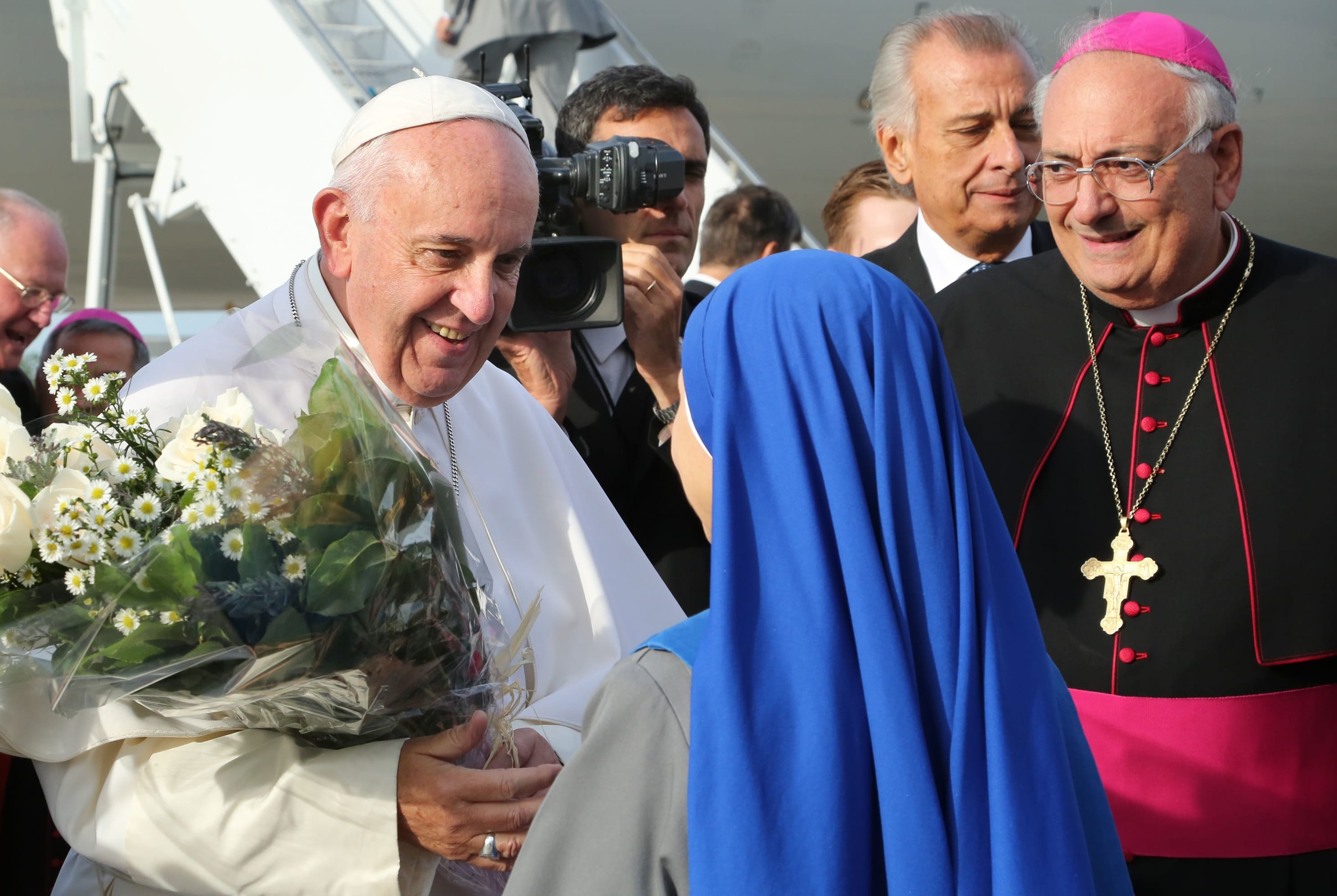 Pope Francis at New York's John F. Kennedy International Airport on September 26, 2015, greeted by nuns from the Monastery of the Precious Blood in Brooklyn, who presented the pontiff with a gift of flowers. Bishop Nicholas DiMarzio (R) of Brooklyn