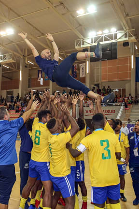 Solomon Islands players throw coach Vinicius Leite into the air in celebration.