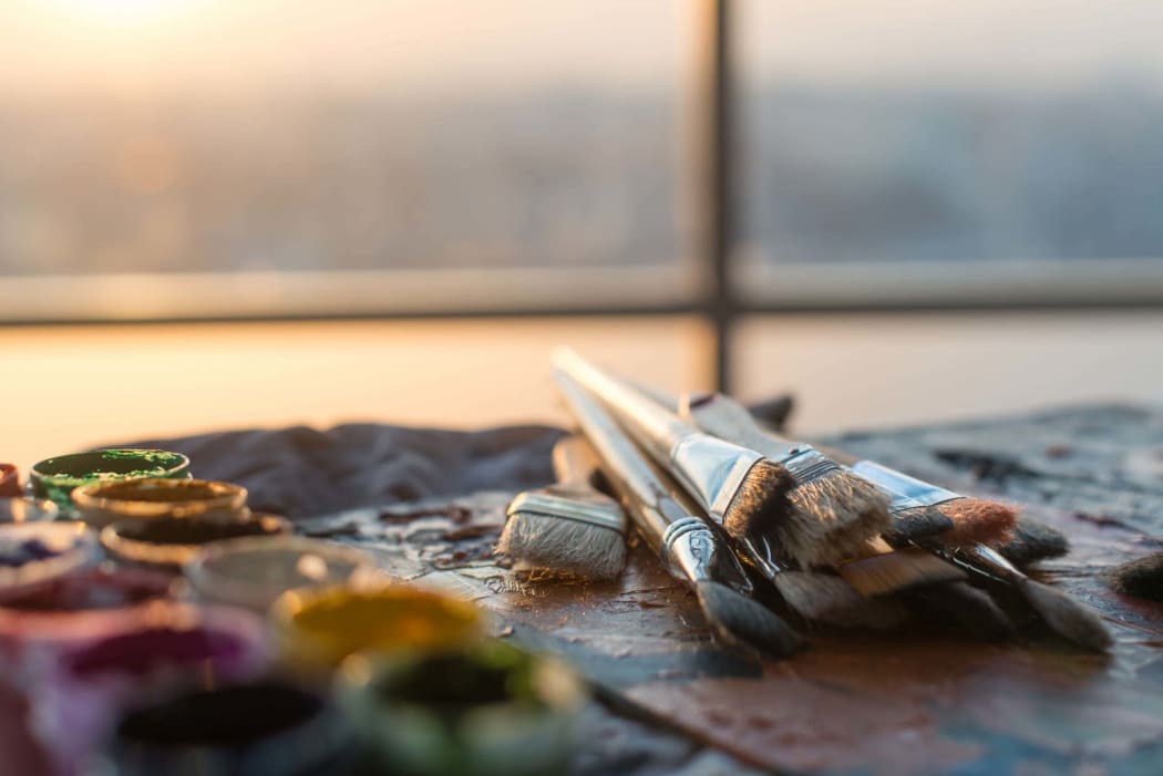 Drawing classes tools in art studio. angle view photo of paintbrushes lying on palette with oil paints brushstrokes mixture