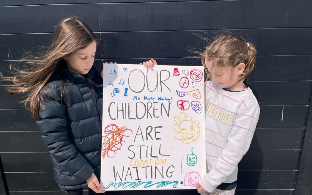 Lillie and Mia Demanser with a sign they will tie to the front gate.