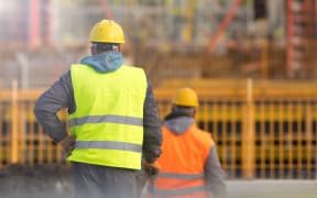 Two builders in yellow and orange at the construction site