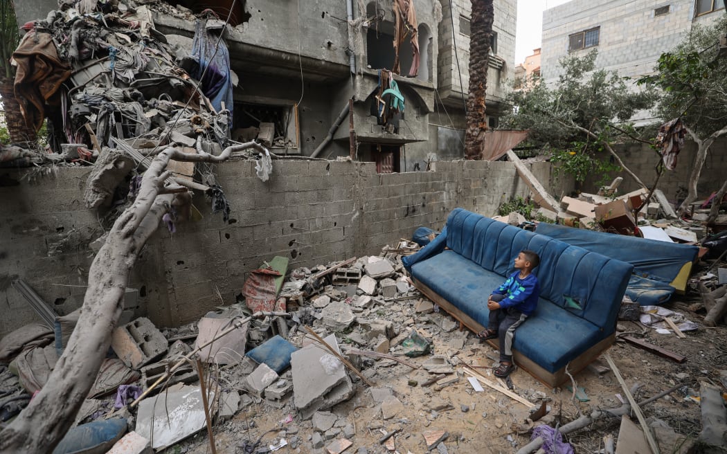 A Palestinian boy sits on a damaged couch as he watches people clearing the rubble from a house that was hit in Israeli strikes at the Nuseirat refugee camp in the central Gaza Strip on May 18, 2025. Gaza's civil defence spokesman Mahmud Bassal told AFP that 22 people were killed and at least 100 others wounded in a predawn attack on tents sheltering displaced Palestinians in Al-Mawasi, in the southern Gaza Strip.