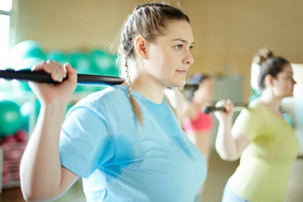 Woman holds bar bell during exercise class.