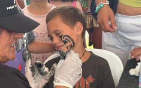Rangatahi at Waitangi ki Waititi festival in West Auckland get ta moko stencils on their face.