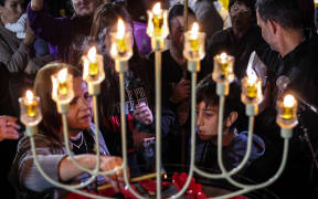 Family members of hostages held by Palestinian militants since the 7 October attack light up a Hanukkiah, a nine-branched menorah candelabrum used in the Jewish holiday of Hanukkah, during a gathering with other hostages' families in Tel Aviv on 14 December, 2023. (Photo by AHMAD GHARABLI / AFP)