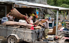 NZDF personnel help throw out sodden belongings at a Tinui property after Cylcone Gabrielle.