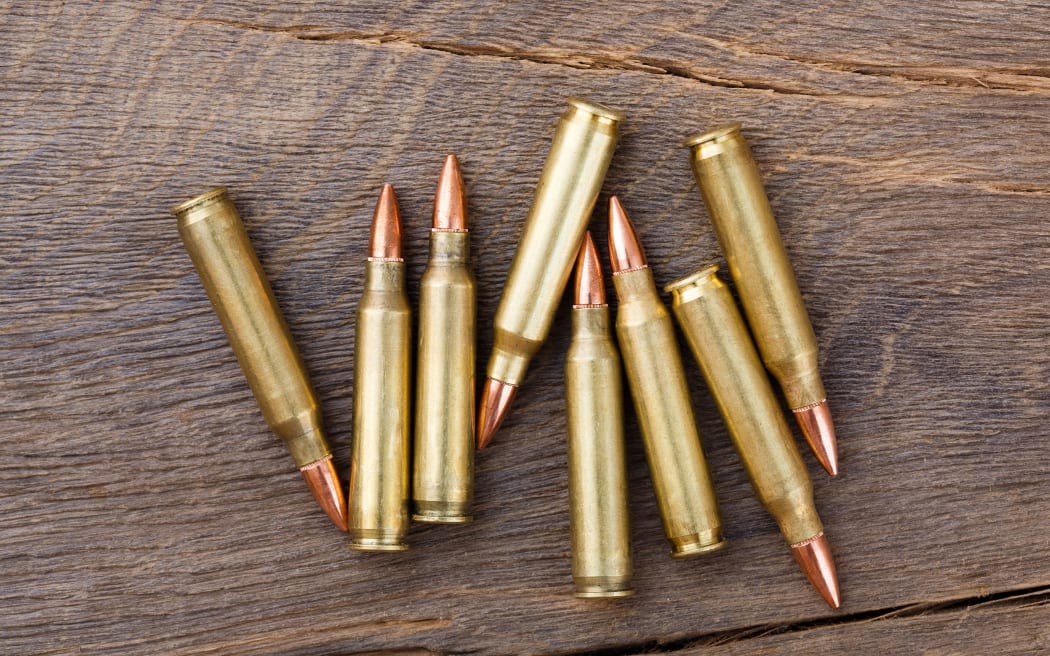 Fire arm or rifle bullet cartridges on a old wooden table.