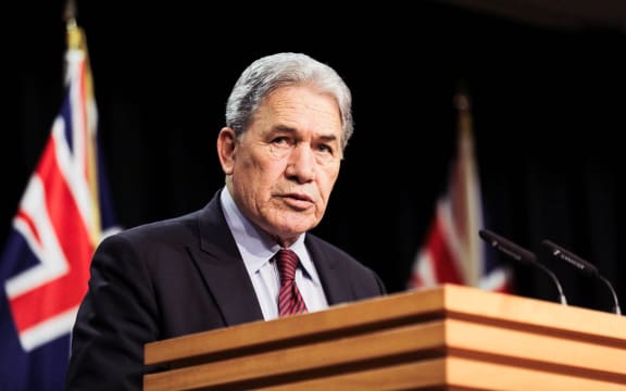 Winston Peters standing in the Beehive Theatre, making an announcement.