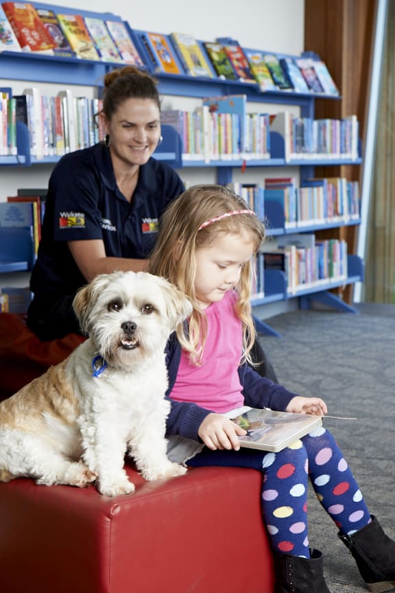 Ivy reads to Charlie Brown, watched by Waikato District Council animal control manager Megan May.