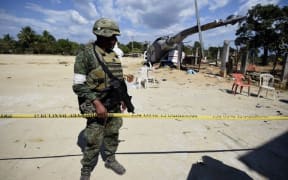 A Mexican soldier stands guard at the site of the accident where a military helicopter fell on a van in Santiago Jamiltepec, Oaxaca state, Mexico.