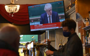 A television screens UK Prime Minister Boris Johnson speaking in the House of Commons, as customers sit at the bar of the Richmond Pub in Liverpool.