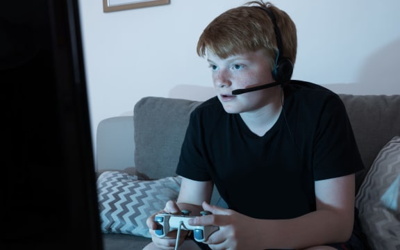 A photo of a boy with a Joystick Engrossed In Playing Videogames in a  darkened room at home